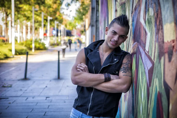 Beau jeune homme contre le mur de graffitis colorés — Photo