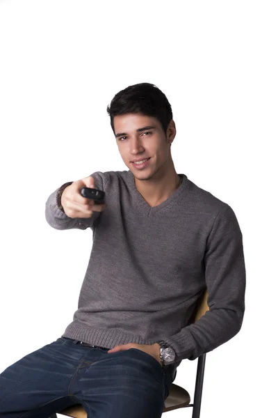 Attractive young man holding remote control and changing TV channels — Stock Photo, Image