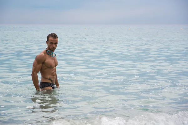 Giovane muscolare bello in piedi nel mare — Foto Stock