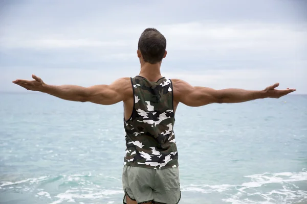 Muscular young man on the beach seen from the back — Stock Photo, Image