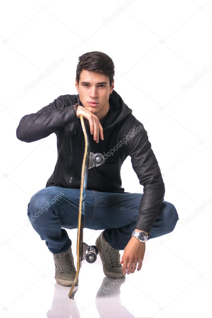 Handsome young man resting head on skateboard