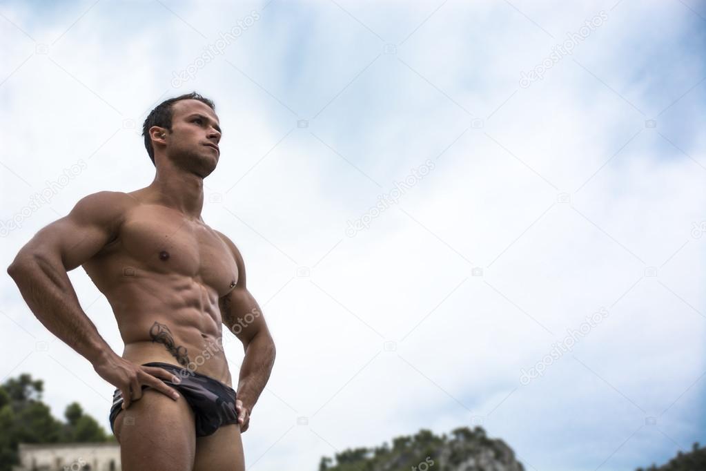 Handsome muscular young man in bathing suit shot from below