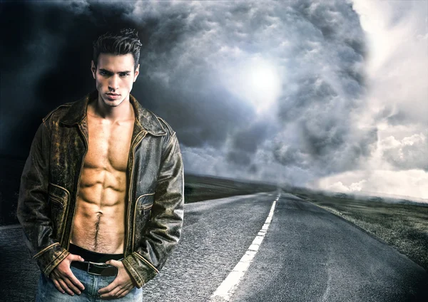 Young man walking down a road with very bad weather far away — Stock Photo, Image