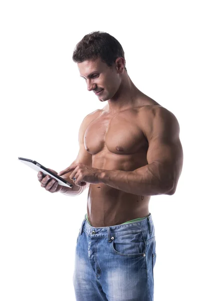Jovem muscular sem camisa segurando o leitor de ebook, em pé — Fotografia de Stock