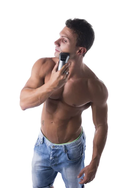 Muscular man shirtless using electric shaver, looking away — Stock Photo, Image