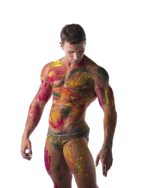 Svalnatý mladý muž bez trička s kůží pomalovanou Holi barvami — Stock fotografie