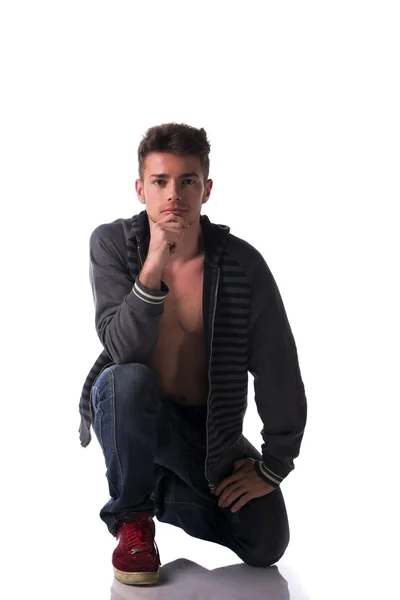 Attractive young man kneeling with sweater on naked torso — Stock Photo, Image