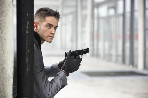 Young detective or policeman or mobster in an urban setting holding a gun — Stock Photo, Image