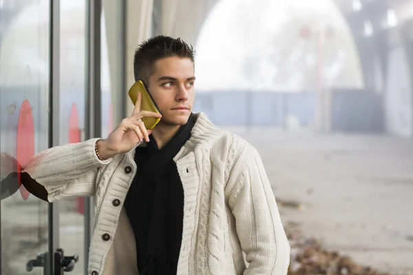 Pohledný mladý muž stojící pomocí mobilního telefonu — Stock fotografie