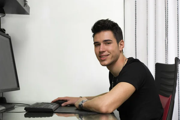 Jovem bonito trabalhando ou studyiing no computador — Fotografia de Stock