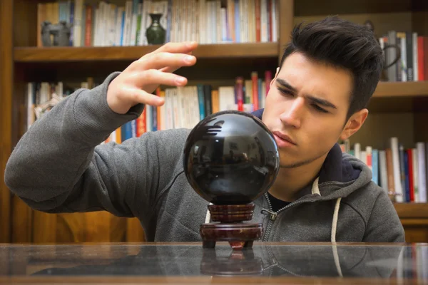 Jonge man voorspellen van de toekomst door te kijken in een kristallen bol — Stockfoto