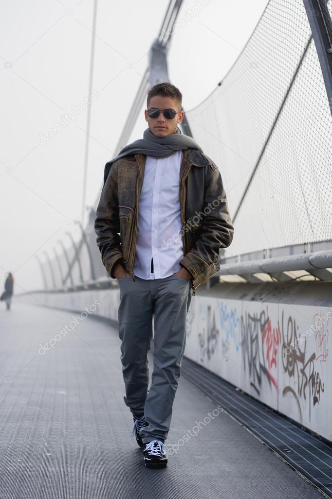 Handsome trendy man walking on a bridge