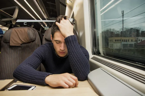 Verveeld moe jonge man op een trein reizen — Stockfoto