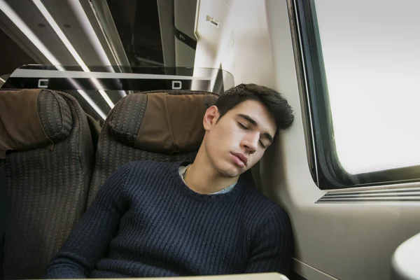 Young man sleeping while traveling on a train sitting in passenger coach — Stock Photo, Image