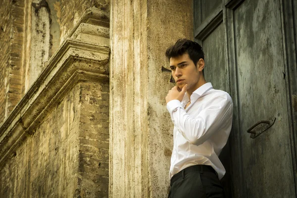 Elegante jongeman leunend tegen oude muur en deur — Stockfoto