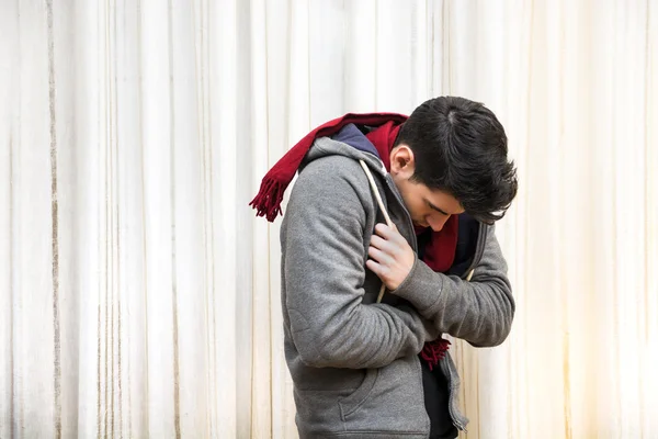 Молодий чоловік відчуває себе дуже холодно, одягнений у важкий светр і шарф — стокове фото