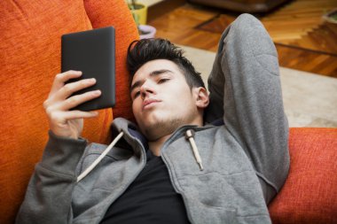 Yakışıklı genç adam evde ebook okuyucu ile okumak