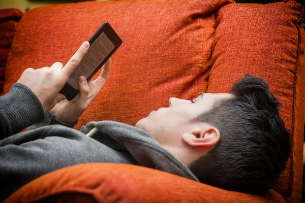 Beau jeune homme à la maison lecture avec lecteur ebook — Photo