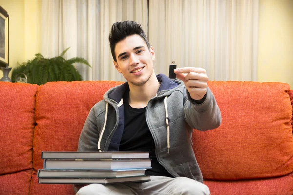 Young man showing difference between USB drive and heavy books — Stock Photo, Image