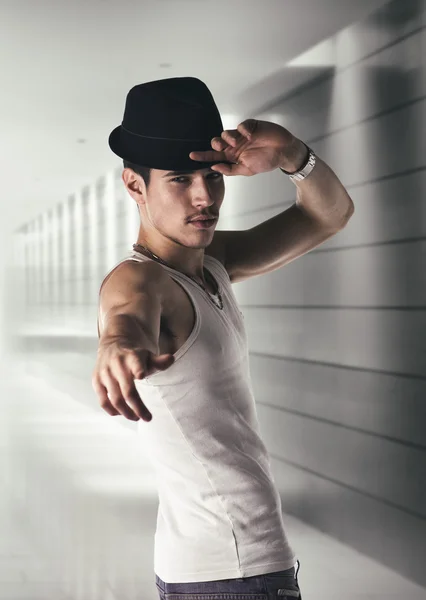 Young man with black fedora in a hallway — Stock Photo, Image