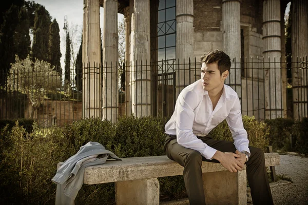 Man in European city, sitting on stone bench — Stock Photo, Image