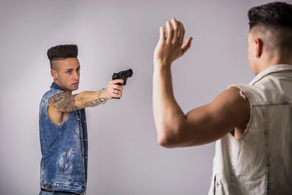 Hombre joven apuntando con un arma a otro chico —  Fotos de Stock