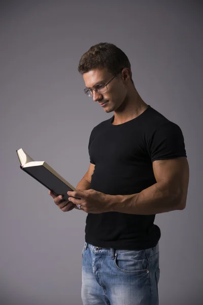 Uomo muscolare che legge grande libro — Foto Stock