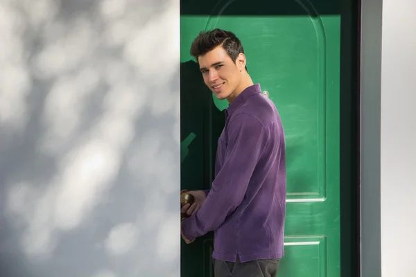 Sorrindo jovem entrando em uma porta de casa — Fotografia de Stock