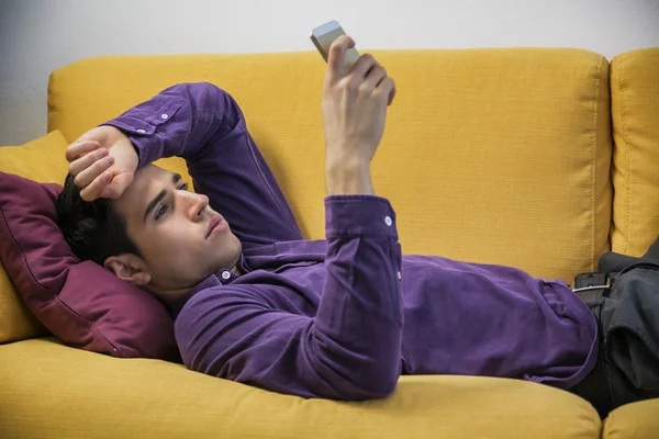 Man using cell phone on couch — Stock Photo, Image