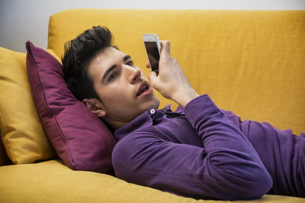 Attractive young man recording voice message on cell phone – stockfoto