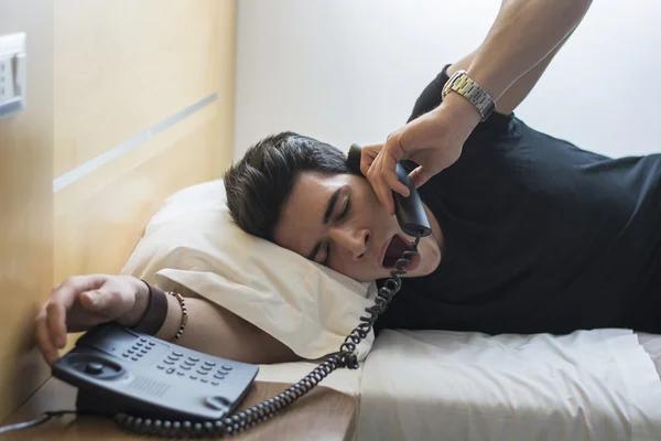 Ospalý muž na posteli zívání při rozhovoru na telefon — Stock fotografie