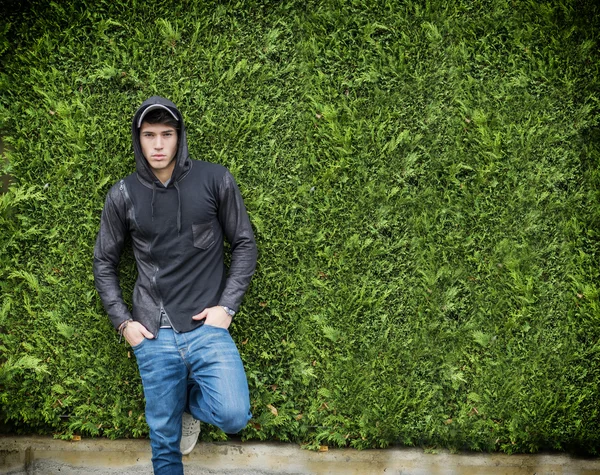 Handsome young man in black hoodie sweater standing outdoor — Stok Foto