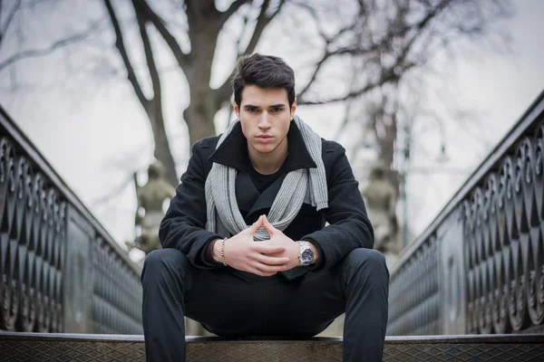 Trendy young man sitting outdoor on old metal bridge — Stock Photo, Image