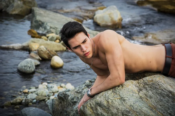 Bello giovane senza camicia che pone sulla roccia di misura — Foto Stock