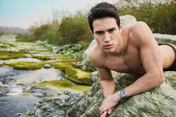 Kayanın üzerinde döşeme uygun gömleksiz yakışıklı genç — Stok fotoğraf