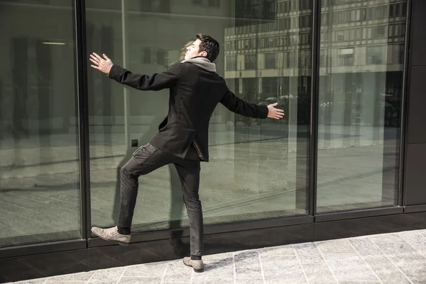 Homem encostado em janela de edifício de escritórios — Fotografia de Stock