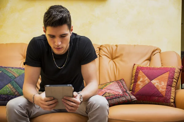 Handsome man at home, using tablet PC – stockfoto