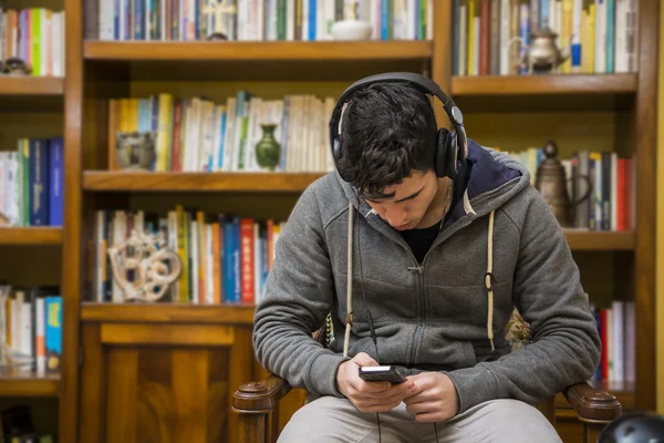 Attractive man sitting listening to music on a set of stereo headphones — Stock Photo, Image