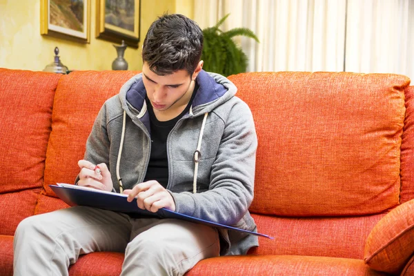 Młody człowiek w domu pisanie na notebooka — Zdjęcie stockowe