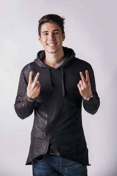 Young man doing peace or victory sign — kuvapankkivalokuva