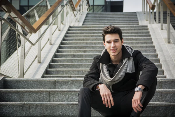 Uzun bir merdiven üzerinde oturan trendy yakışıklı adam — Stok fotoğraf