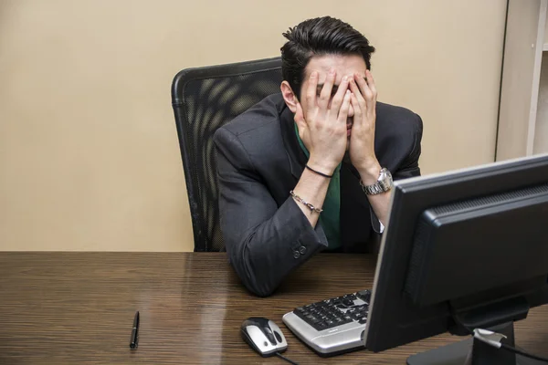 Jeune homme d'affaires inquiet assis à son bureau — Photo