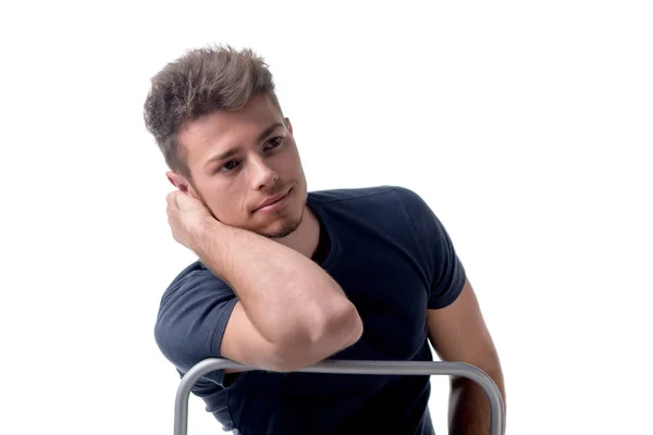 Young man sitting, leaning on back of a chair — Stock Photo, Image