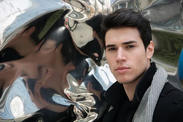 Handsome young man next to deforming mirror — Stock Photo, Image