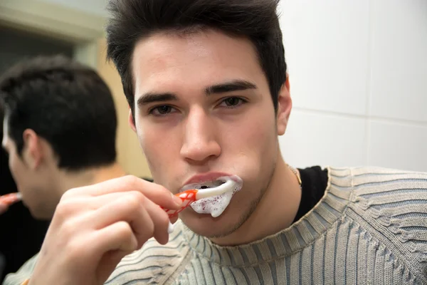 Headshot of attractive young man brushing teeth — Stok Foto