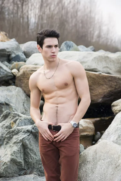 Sportowy młody człowiek bez koszuli na świeżym powietrzu nad rzeką lub strumieniem wody — Zdjęcie stockowe