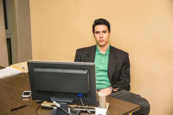Allvarlig ung affärsman sitter vid skrivbord i office — Stockfoto