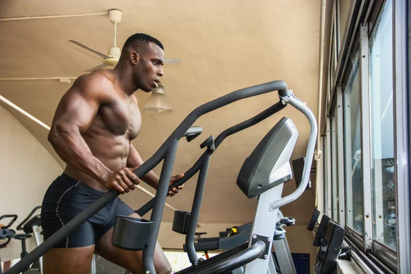 Black male bodybuilder exercising on step machine — Stock Photo, Image