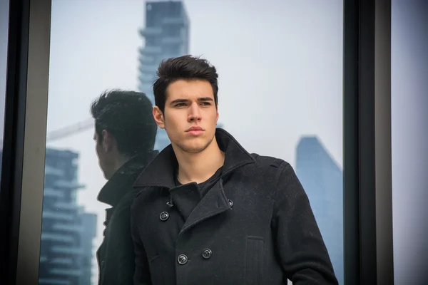 Junger Mann, der im freien gegen Bürofenster — Stockfoto