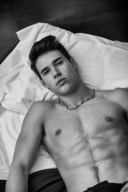 Gömleksiz atletik genç adam yatakta döşeme